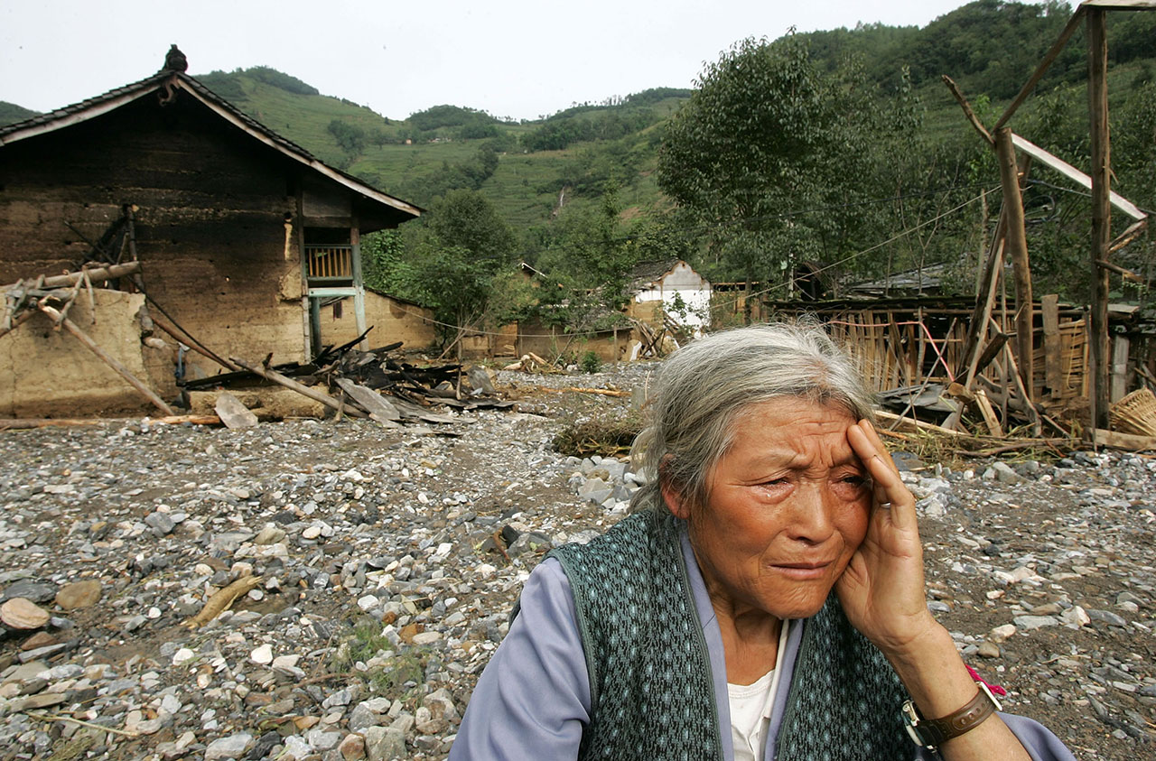 四川广元一名老妇坐在她被洪灾毁坏的家门前 (美联社资料图)